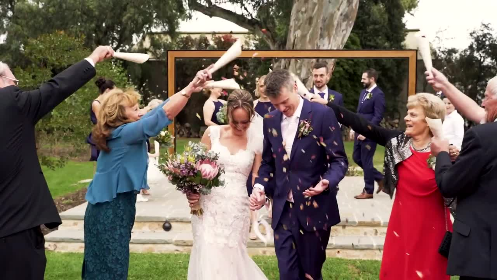 Bride and groom walking down the aisle with guests celebrating